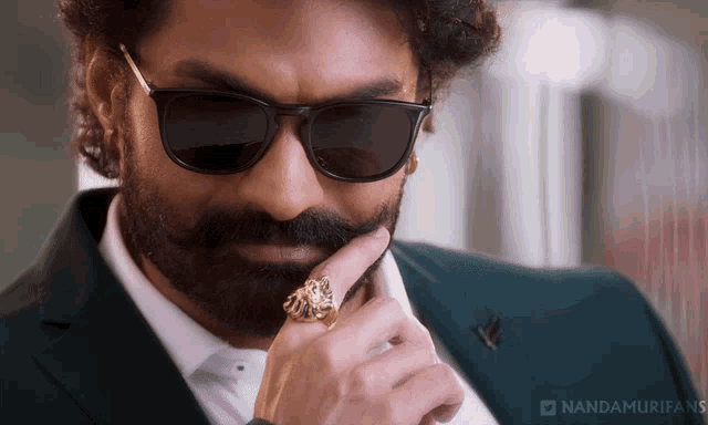 a man with a beard wearing sunglasses and a ring with the hashtag nandamurifans on the bottom