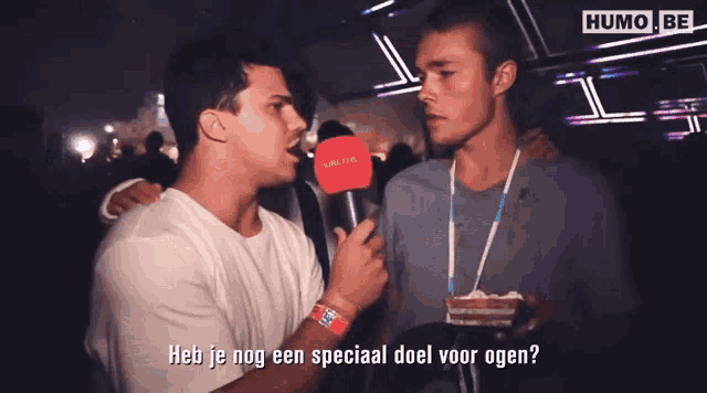 a man holding a microphone talking to another man with the words heb je nog een special doel voor ogen