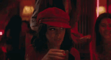 a woman is drinking from a glass in a bar .