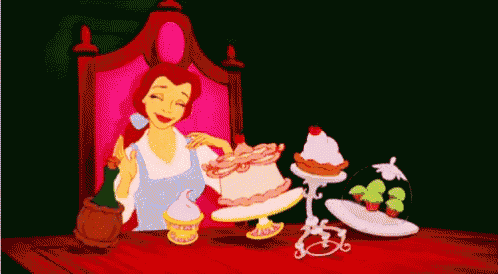 belle from beauty and the beast is sitting at a table with a cake on it