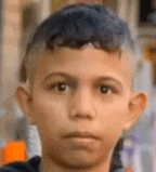 a young boy with blue hair is looking at the camera and making a funny face .