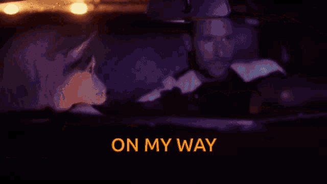 a man is driving a car at night with the words on my way written above him