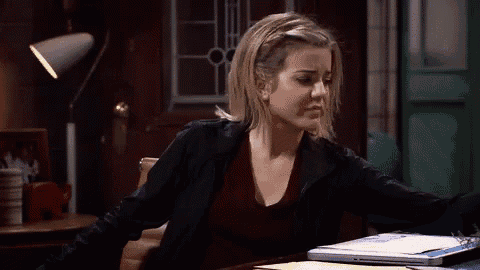a woman is yawning while sitting at a desk in front of a laptop .