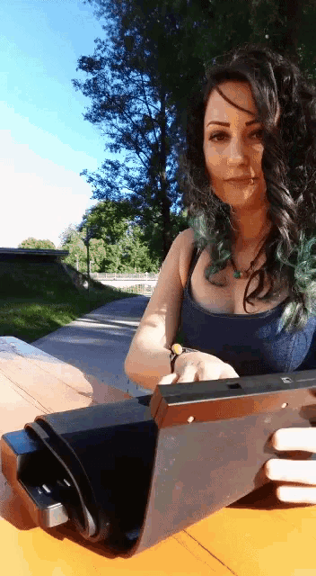 a woman with green hair sits at a table holding a tablet