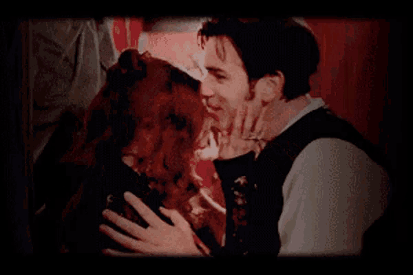 a man is kissing a woman on the cheek while they are hugging .