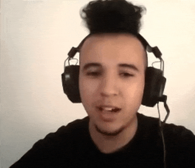 a man wearing headphones with a bun on his head is talking on a video call .