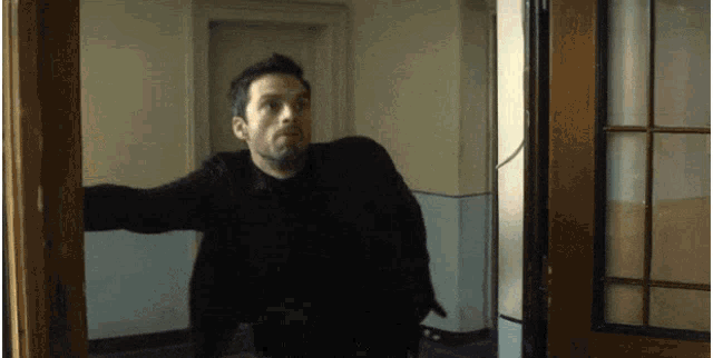 a man in a black shirt is standing in a hallway