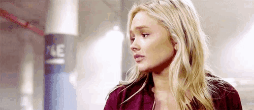 a woman with blonde hair is standing in a parking garage looking at the camera .