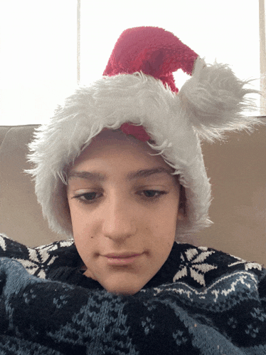 a young boy wearing a santa hat and sweater