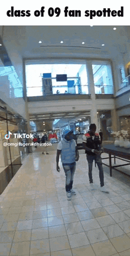 two men are walking in a mall with the caption class of 09 fan spotted .