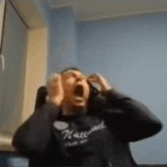 a man wearing headphones is screaming with his mouth open in a room .