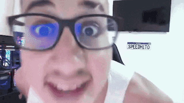 a close up of a person wearing glasses with a license plate that says speedmito