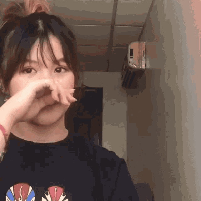 a girl covering her nose with her hand in a room with an air conditioner