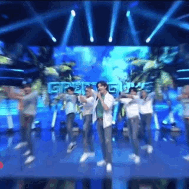 a group of people are standing on a stage with a large screen behind them that says gree