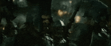 a large group of soldiers are marching through a dark forest in a battle scene .
