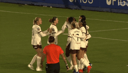 a group of female soccer players huddle on the field with one wearing the number 30