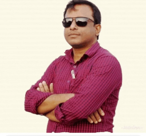 a man with his arms crossed wearing sunglasses and a plaid shirt