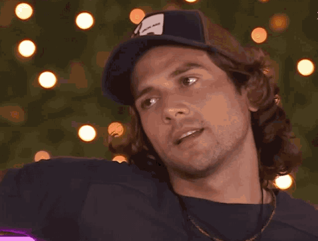 a man with long hair wearing a hat that says ' goat ' on it