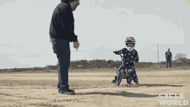 a man pointing at a child on a bike with cycle world written on the bottom right