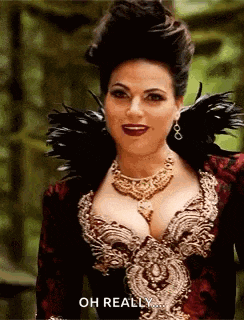 a woman in a very revealing dress is standing in the woods and talking to the camera .