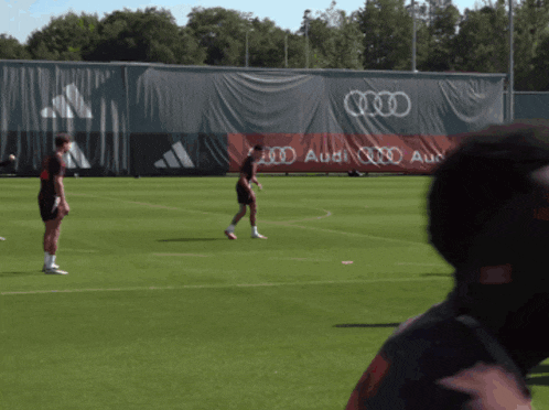 soccer players on a field with a large audi banner behind them