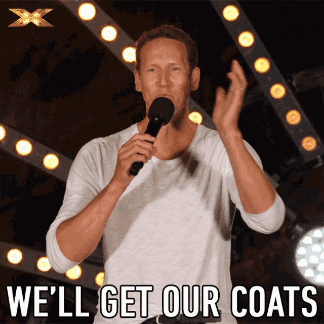 a man holding a microphone with the words we 'll get our coats below him