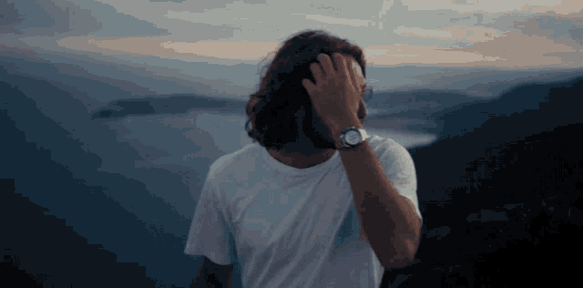 a man covering his face with his hand and wearing a watch