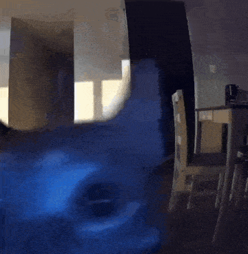 a room with a table and chairs and a blue light coming out of the door