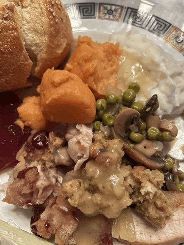 a plate of turkey dinner with mashed potatoes peas and gravy