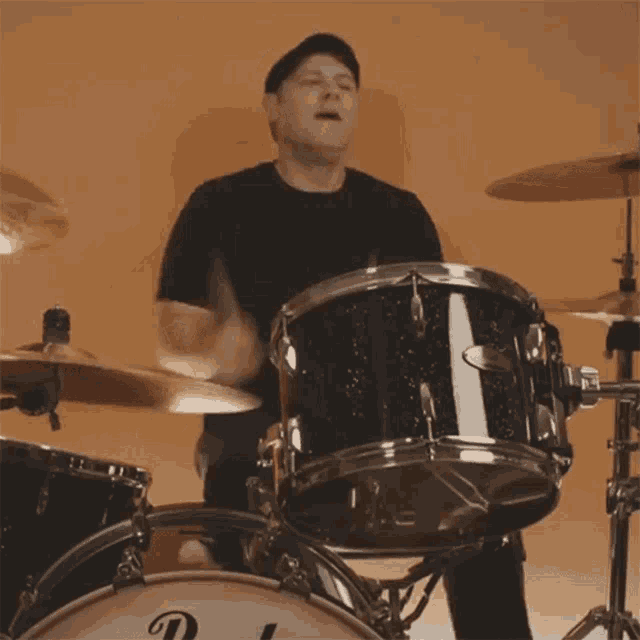 a man is playing a drum set with the letter d on the drum