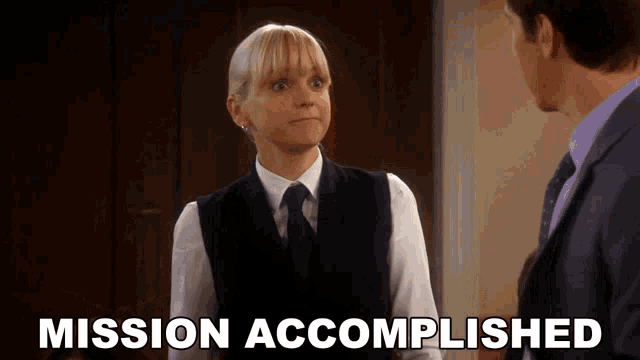 a woman in a vest and tie stands next to a man and the words mission accomplished are visible