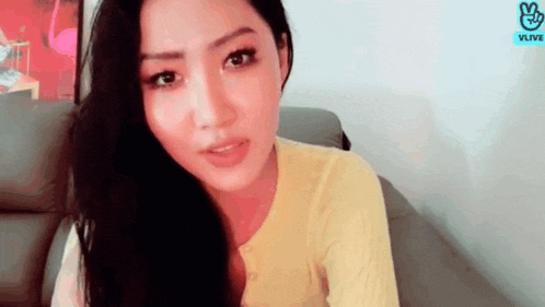 a woman in a yellow sweater is sitting on a couch .