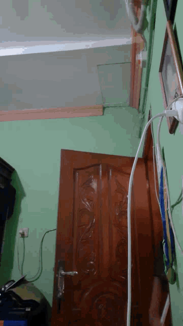 a green wall with a wooden door and a white cord