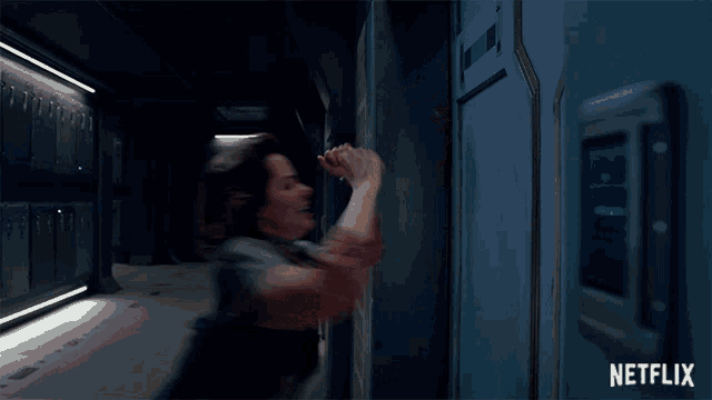 a woman standing in a dark hallway with a netflix logo in the corner