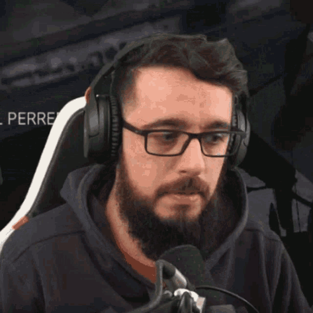 a man with glasses and headphones is sitting in front of a microphone .