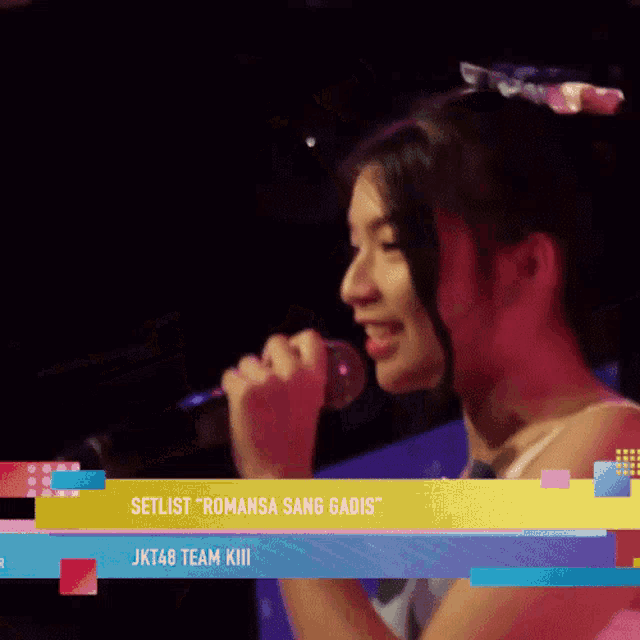 a woman singing into a microphone with the words setlist romansa sang gadis jkt48 team kill below her