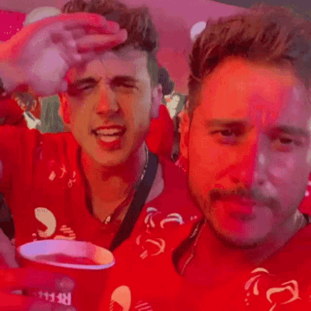 two men are standing next to each other and one of them is wearing a red shirt that says ' a ' on it