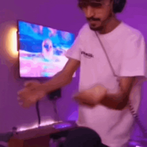 a man wearing headphones is playing a video game in front of a television in a purple room .