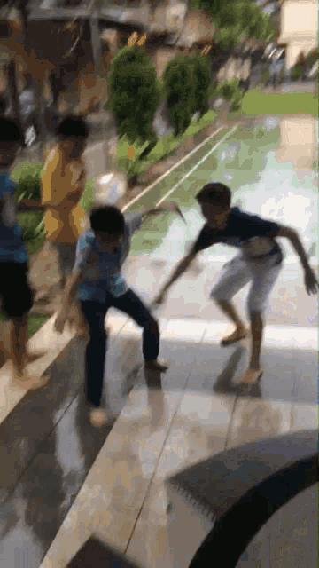 a group of boys are playing with a ball on the sidewalk