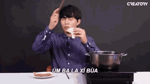 a man is sitting at a table with a plate of food and a pot of water .