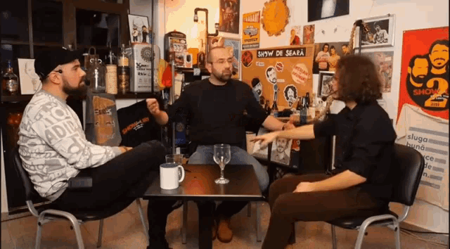 three men sit at a table with a sign that says show de seara on it