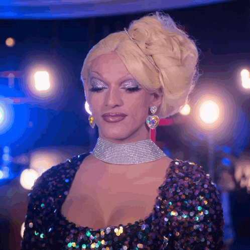 a drag queen wearing a purple sequined dress and earrings