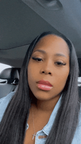 a woman with long hair is sitting in the back seat of a car looking at the camera