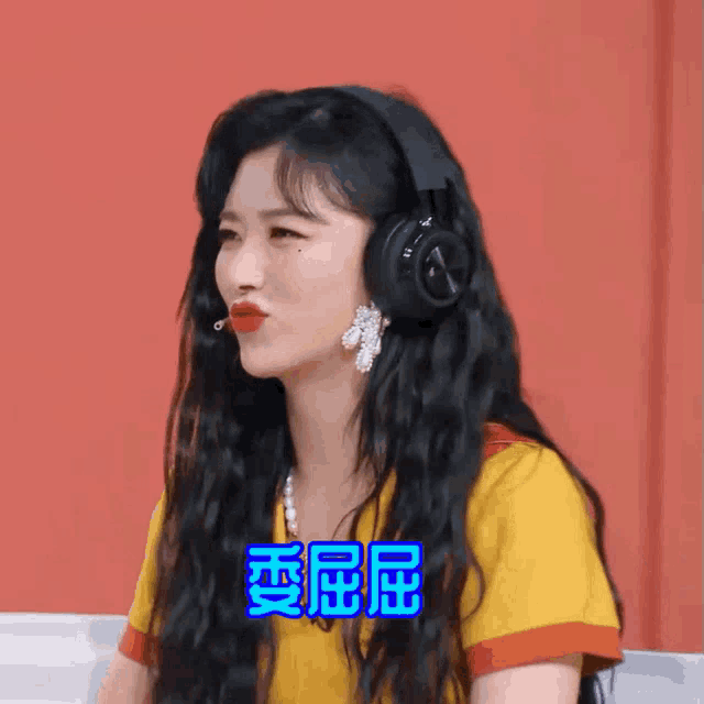 a woman wearing headphones and a yellow shirt with chinese writing on the bottom