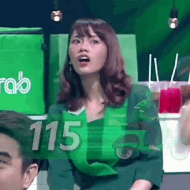 a woman in a green apron with the number 115 on it