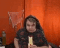 a man wearing headphones is eating a sandwich in front of an orange curtain .