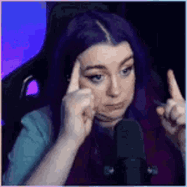a woman with purple hair is sitting in a chair in front of a microphone .