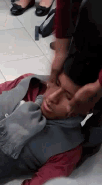 a man is laying on the floor being held by a woman
