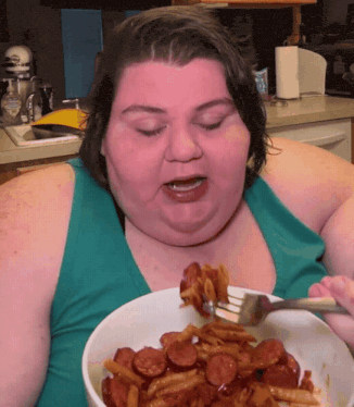 a woman in a blue tank top is eating a bowl of food