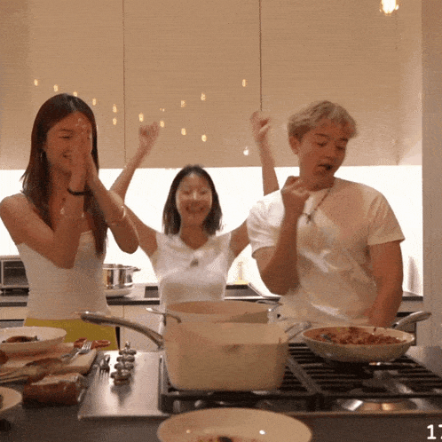 a man and two women are cooking in a kitchen with the number 11 on the counter